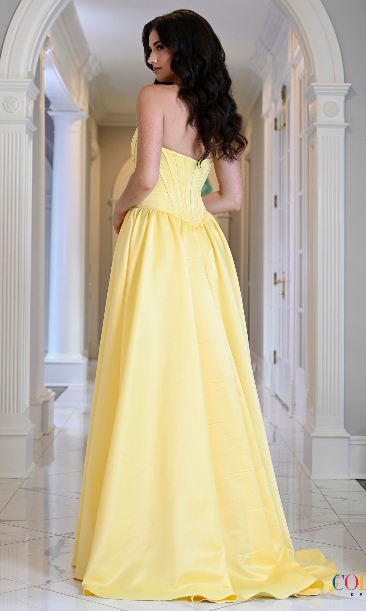 A woman in a strapless, floor-length yellow corset Long Prom Dress: Colors Dress 3997 stands in a hallway.
